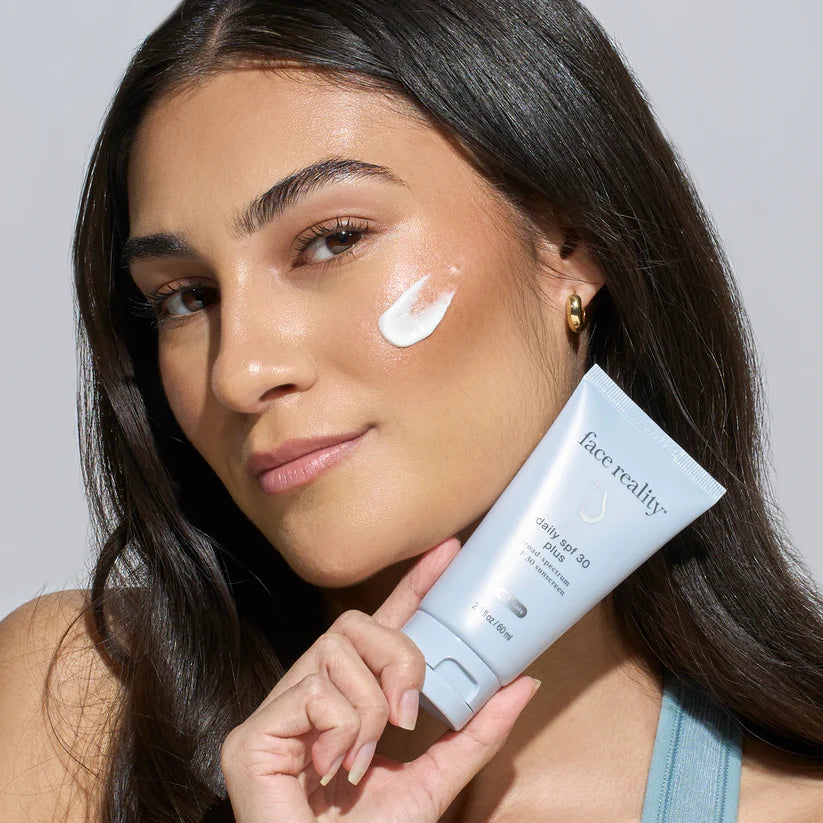 Woman applying face reality daily spf 30 plus cream to her face
