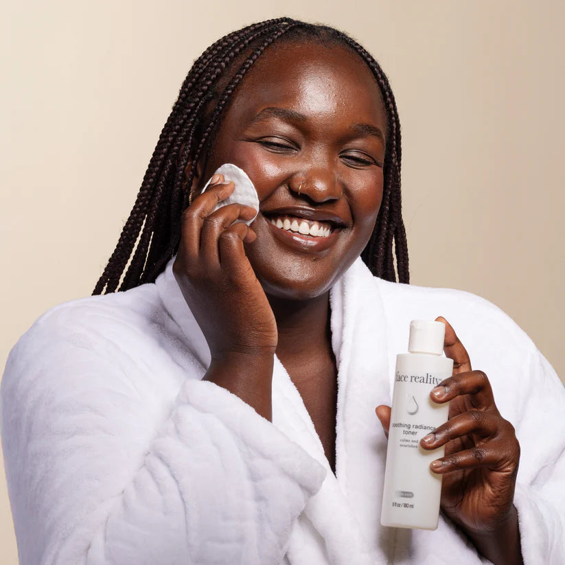 Woman applying skincare product with a bottle of Face Reality Soothing Radiance Toner on a beige background
