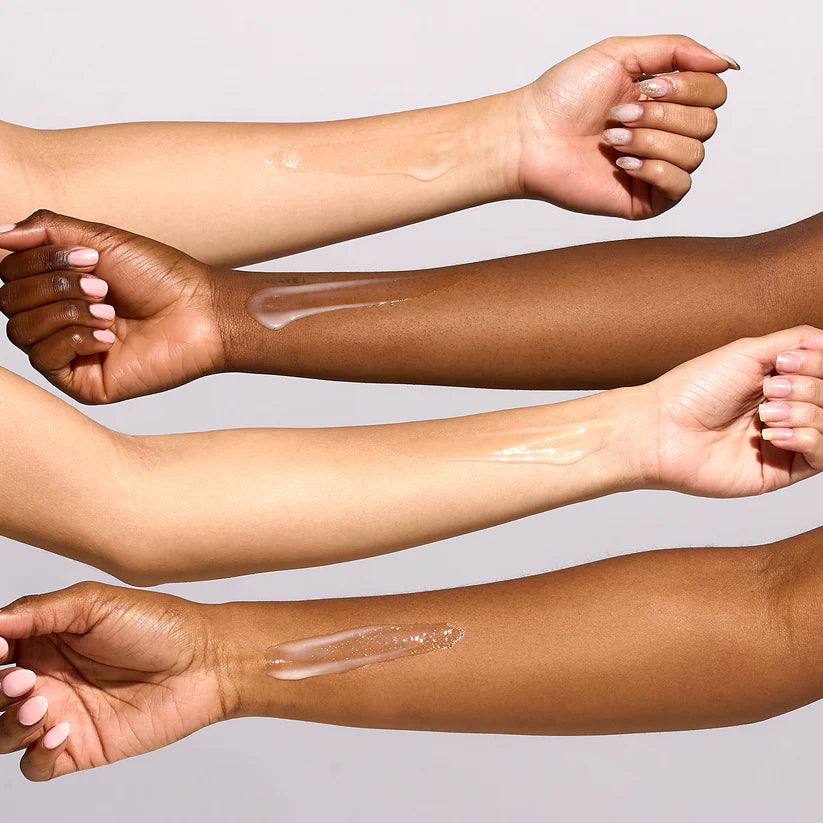 Four arms with different skin tones showing glow tone serum