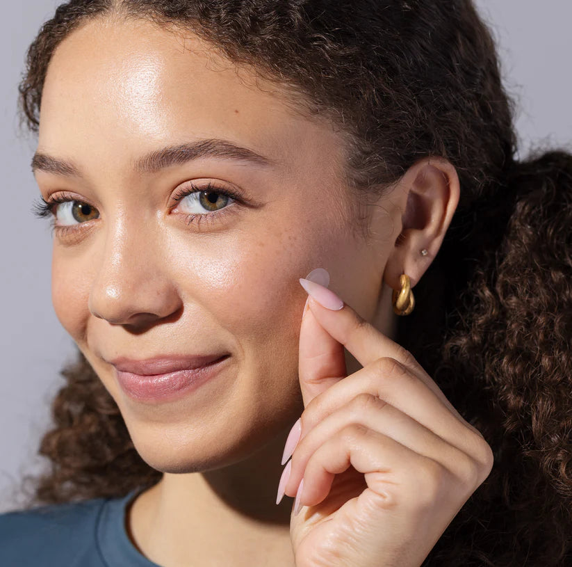 Woman applying InvisiClear hydrocolloid pimple patch